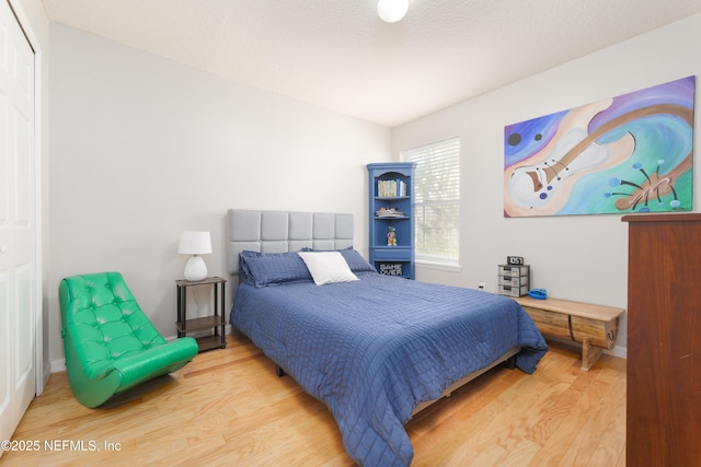 bedroom with a closet, baseboards, and wood finished floors