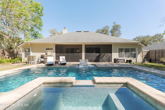 view of swimming pool with a sunroom, a pool with connected hot tub, and fence