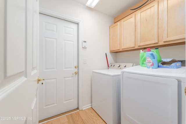 clothes washing area with cabinet space, light wood-style floors, and washing machine and clothes dryer