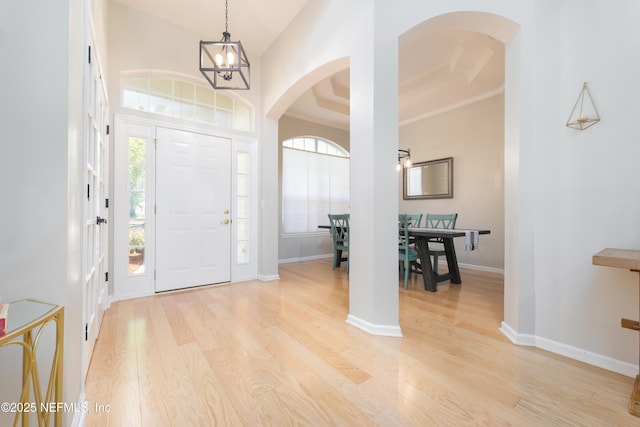 foyer with baseboards, arched walkways, and wood finished floors