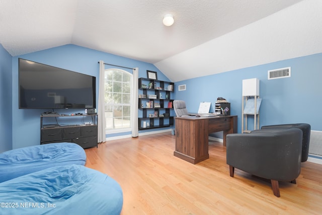 office space featuring visible vents, lofted ceiling, a textured ceiling, and wood finished floors