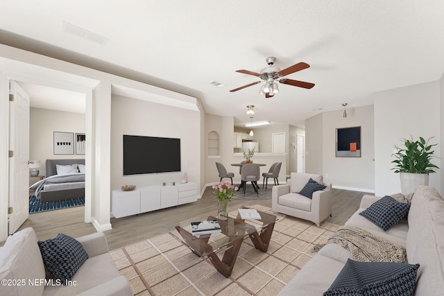 living area featuring light wood-style floors, visible vents, ceiling fan, and baseboards