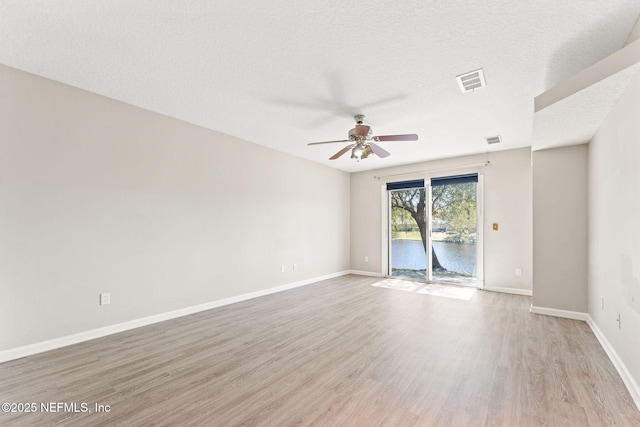 spare room featuring visible vents, a textured ceiling, light wood-style flooring, and baseboards