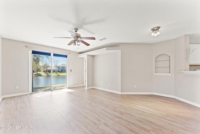 empty room with visible vents, a textured ceiling, baseboards, and wood finished floors