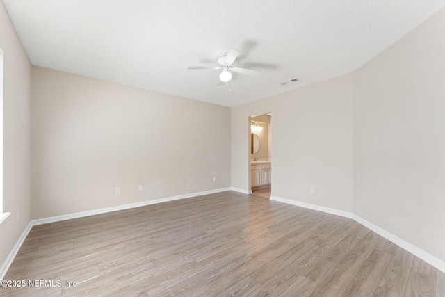 unfurnished room with visible vents, baseboards, a ceiling fan, light wood-style flooring, and a textured ceiling