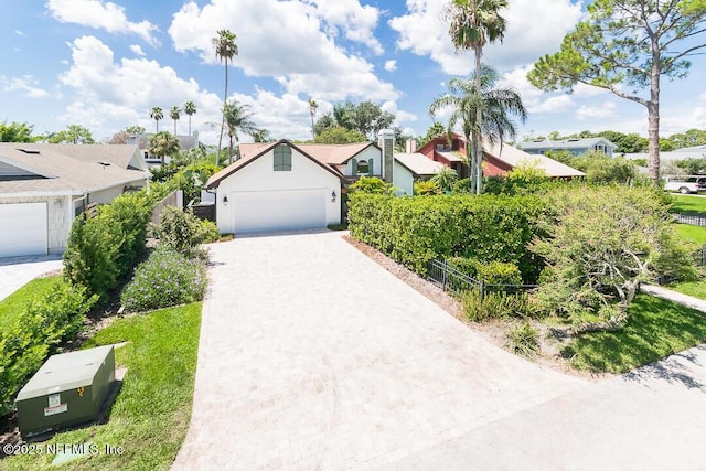 view of front of house with a residential view, decorative driveway, fence, and an attached garage