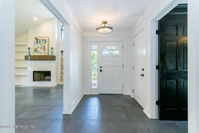 foyer entrance with a high end fireplace and baseboards