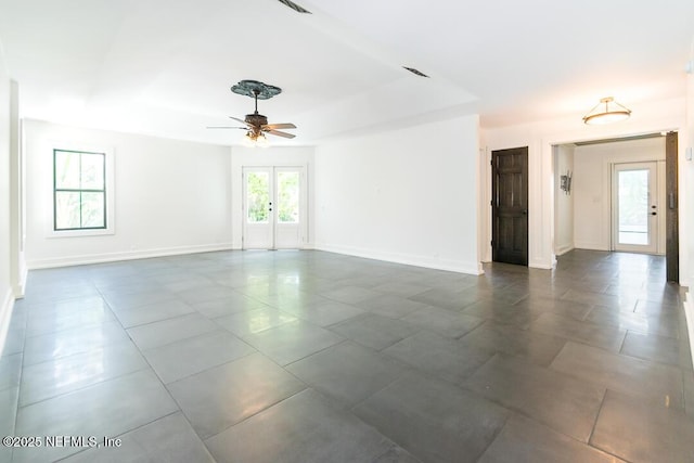 empty room with french doors, a raised ceiling, visible vents, and baseboards