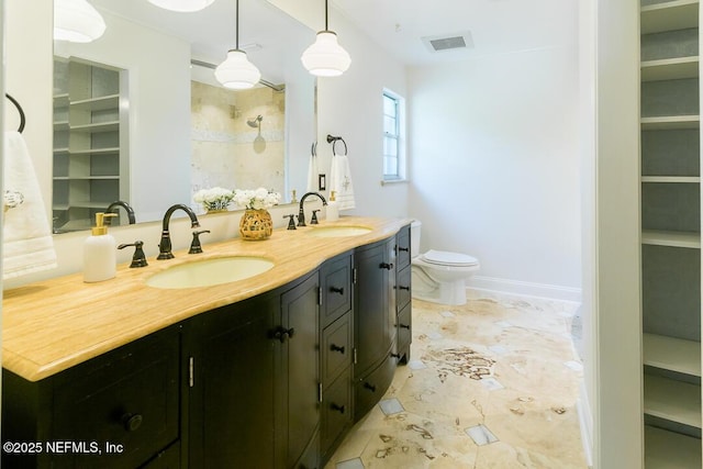 bathroom with toilet, double vanity, a sink, and visible vents