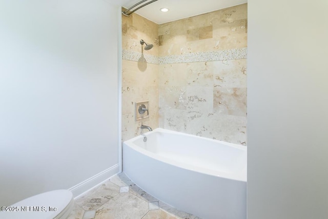 bathroom with baseboards, shower / tub combination, and toilet