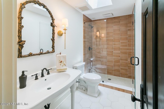 full bathroom featuring a stall shower, a sink, toilet, and tile patterned floors