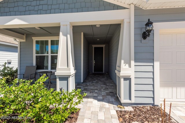 view of exterior entry featuring a porch and an attached garage