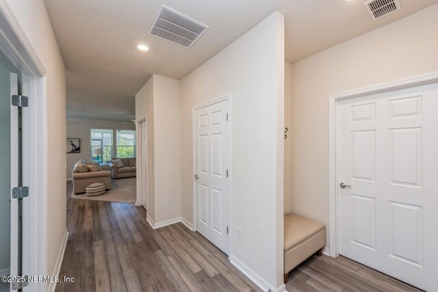 corridor with visible vents, baseboards, and wood finished floors