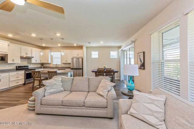 living area featuring a textured ceiling, a ceiling fan, dark wood-style flooring, and recessed lighting