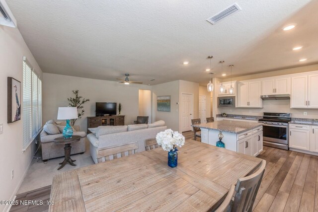 dining room with baseboards, visible vents, wood finished floors, a textured ceiling, and recessed lighting