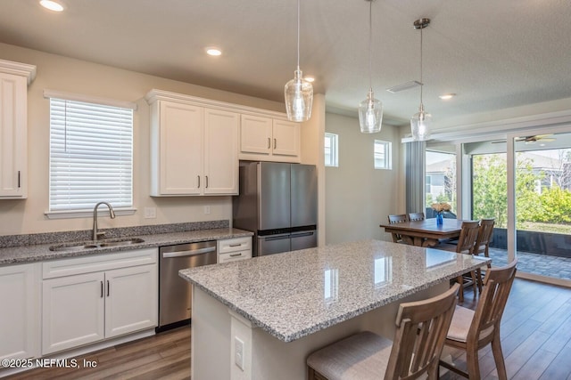 kitchen featuring a breakfast bar area, stainless steel appliances, wood finished floors, a kitchen island, and a sink