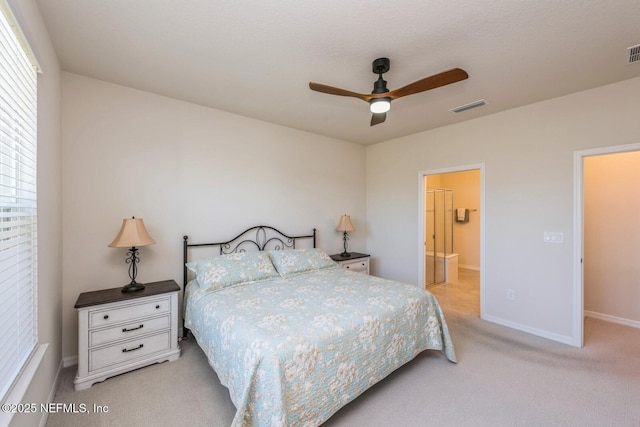 carpeted bedroom with ceiling fan, connected bathroom, visible vents, and baseboards