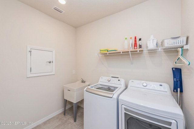 laundry area featuring washer and clothes dryer, visible vents, light tile patterned flooring, laundry area, and baseboards