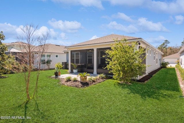 back of property with a sunroom, a patio area, and a lawn