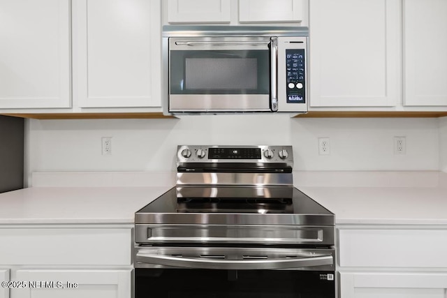 kitchen with appliances with stainless steel finishes, light countertops, and white cabinets