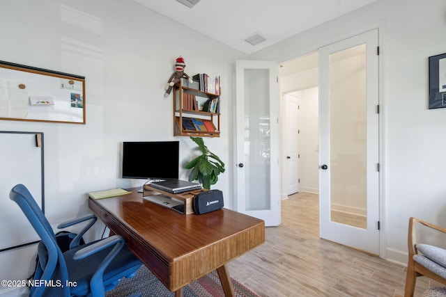 home office featuring light wood-type flooring, french doors, and visible vents