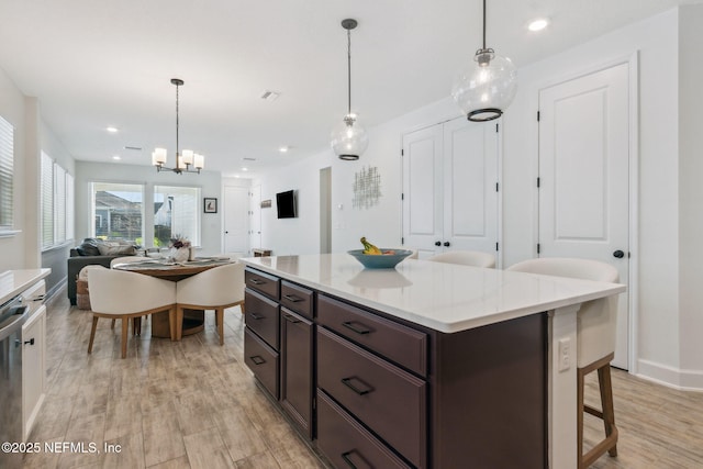 kitchen with light countertops, light wood-style flooring, open floor plan, dark brown cabinetry, and dishwasher