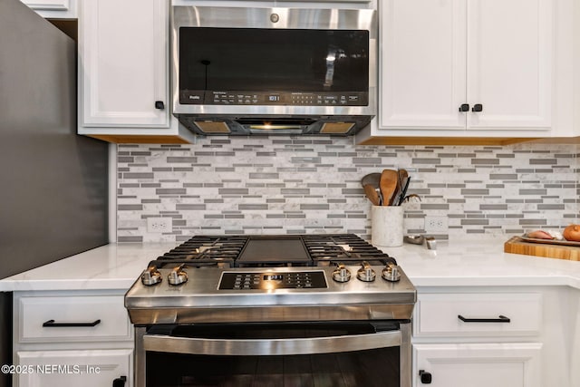 kitchen with appliances with stainless steel finishes, light countertops, white cabinets, and tasteful backsplash