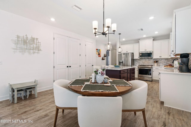 dining area with baseboards, visible vents, an inviting chandelier, light wood-style floors, and recessed lighting