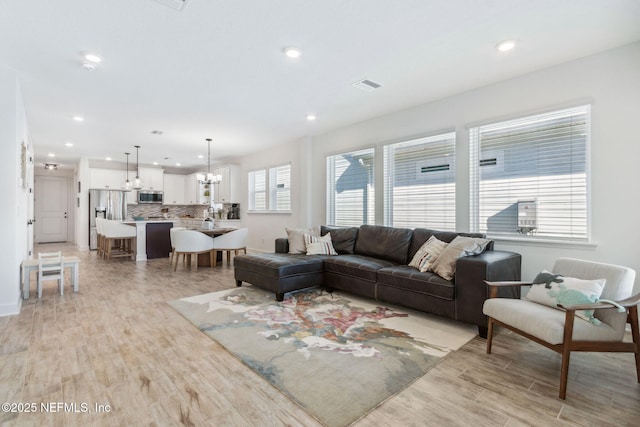 living area featuring an inviting chandelier, visible vents, light wood-style floors, and recessed lighting