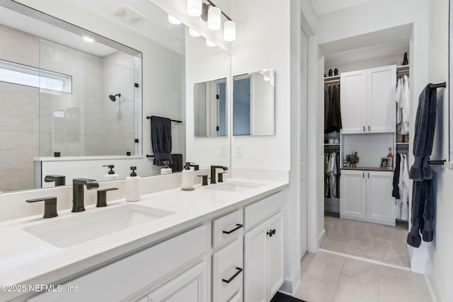 bathroom featuring double vanity, tile patterned floors, a sink, and tiled shower