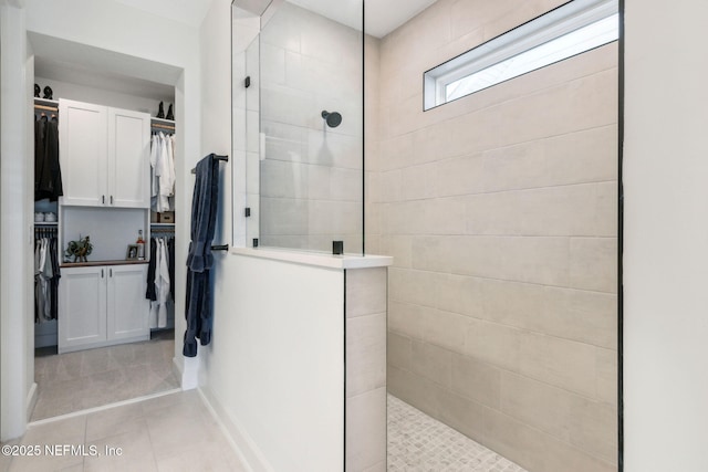 full bathroom featuring tile patterned flooring, a spacious closet, and walk in shower