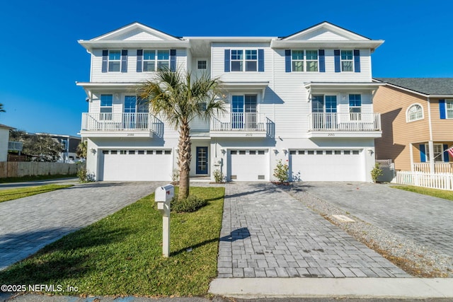 beach home featuring a garage, decorative driveway, and fence