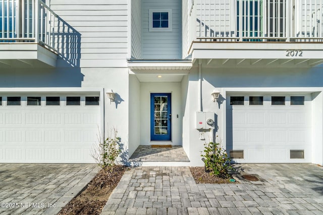 2072 Gail Ave, Jacksonville Beach, FL 32250 - doorway to property with stucco siding, an attached garage, decorative driveway, and a balcony