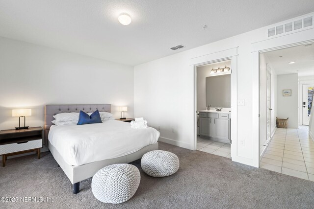 2072 Gail Ave, Jacksonville Beach, FL 32250 - bedroom featuring light tile patterned floors, visible vents, light colored carpet, and connected bathroom