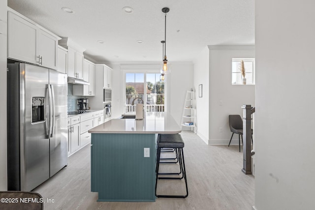 2072 Gail Ave, Jacksonville Beach, FL 32250 - kitchen featuring under cabinet range hood, ornamental molding, stainless steel appliances, white cabinetry, and a kitchen island with sink