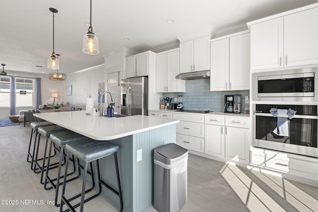 2072 Gail Ave, Jacksonville Beach, FL 32250 - kitchen with a kitchen island with sink, a sink, under cabinet range hood, tasteful backsplash, and stainless steel appliances