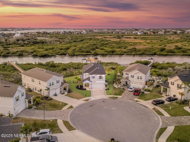 aerial view at dusk with a water view and a residential view