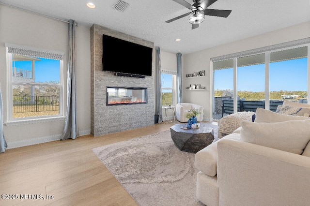 living room with plenty of natural light, a fireplace, wood finished floors, and visible vents