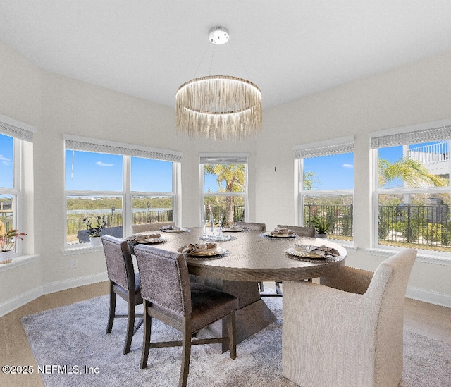 dining space featuring baseboards, wood finished floors, and an inviting chandelier