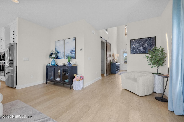 living area featuring light wood-type flooring, baseboards, and a barn door