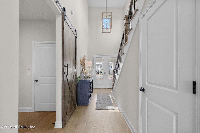 foyer with stairway, a barn door, a high ceiling, and baseboards