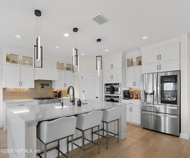 367 Five Island Dr, Saint Augustine, FL 32080 - kitchen with glass insert cabinets, white cabinets, visible vents, stainless steel appliances, and light wood finished floors