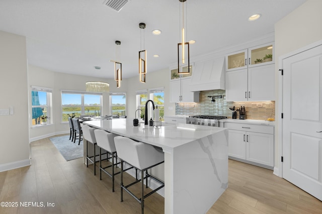 367 Five Island Dr, Saint Augustine, FL 32080 - kitchen with visible vents, an island with sink, premium range hood, light wood-type flooring, and backsplash