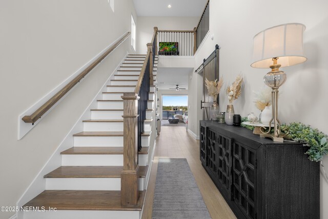 367 Five Island Dr, Saint Augustine, FL 32080 - stairway with a towering ceiling, baseboards, recessed lighting, a barn door, and wood finished floors