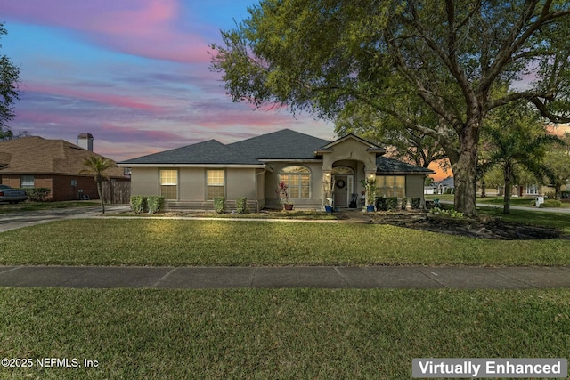 view of front of home featuring a lawn and stucco siding