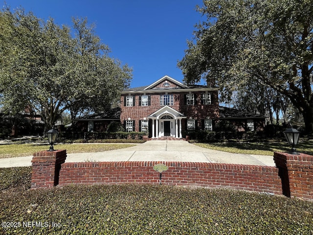 colonial inspired home featuring brick siding and a front lawn