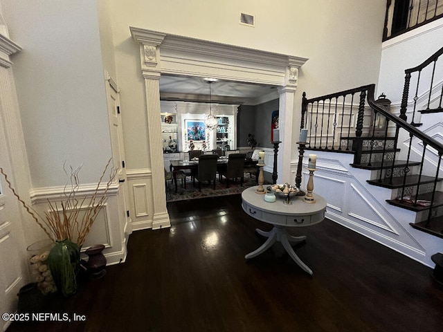 foyer with visible vents, stairway, a decorative wall, and wood finished floors