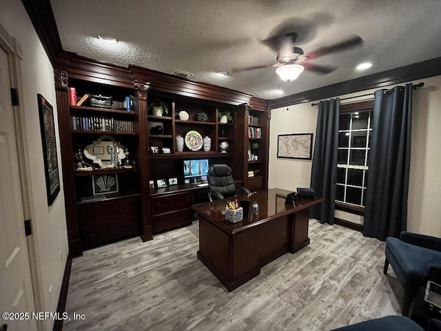 office space featuring a ceiling fan, visible vents, light wood finished floors, a textured ceiling, and crown molding