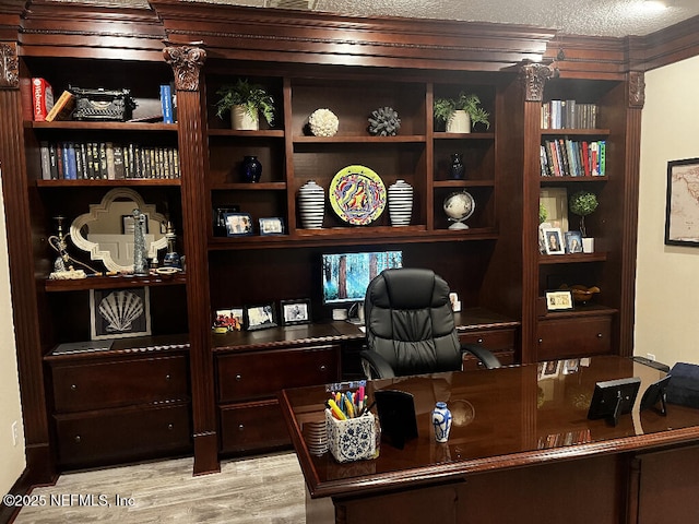 home office with light wood finished floors and a textured ceiling