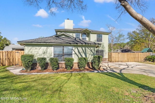 traditional home featuring brick siding, a chimney, a front yard, and fence